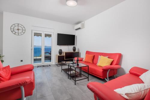 a living room with two red couches and a television at Apartment Kvarner View in Kostrena