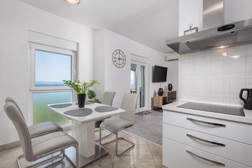 a kitchen with a table and chairs in a kitchen at Apartment Kvarner View in Kostrena