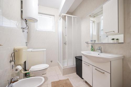 a white bathroom with a toilet and a sink at Villa Stone House with Pool in Nin