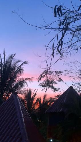 a view of a sunset with palm trees and a building at Casa Tropical Playa Grande in Cuajiniquil