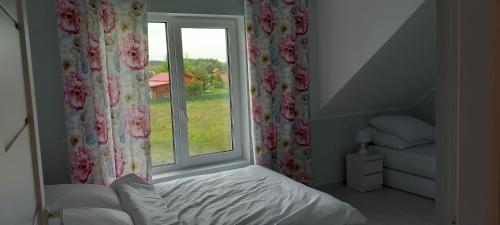 a bedroom with a bed and a window with flowers at Mazurskie Wzgórze BIS z basenem.3i4 in Rydzewo