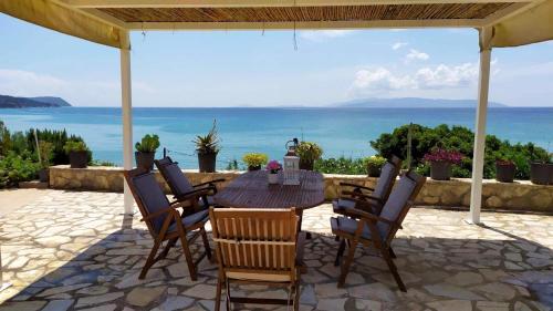 un tavolo in legno con sedie e vista sull'oceano sullo sfondo di NIKOS & SPIROS a Trapezaki
