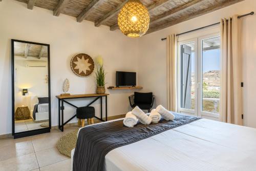 1 dormitorio con cama, escritorio y ventana en Aurora Mykonos Villas, en Kalafatis
