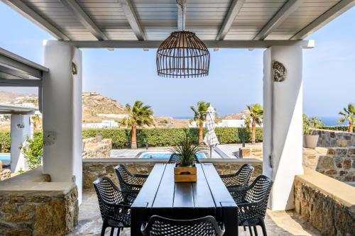 a dining table on a patio with a view of a pool at Aurora Mykonos Villas in Kalafatis