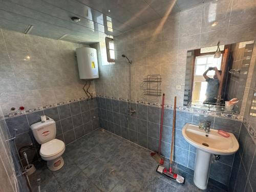 a man taking a picture of a bathroom with a toilet and sink at Vandam Luminous Villa in Gabala