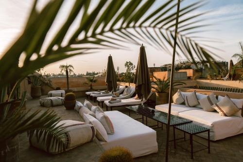 eine Terrasse mit weißen Sofas und Sonnenschirmen in der Unterkunft Riad K in Marrakesch