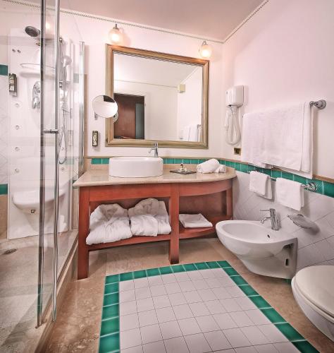 a bathroom with a sink and a toilet and a mirror at Hotel Villa Capri in Gardone Riviera