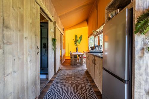 een keuken met gele muren en een roestvrijstalen koelkast bij Sunny Trio in Zeewolde