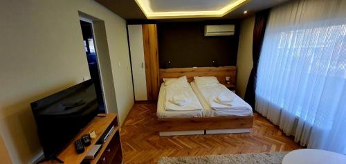 a small bedroom with a bed and a flat screen tv at Ivet Guest rooms in Varna City