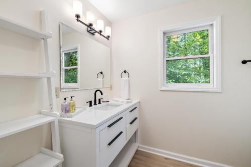 ein weißes Badezimmer mit einem Waschbecken und einem Spiegel in der Unterkunft Heron Hideaway in Wilkesboro