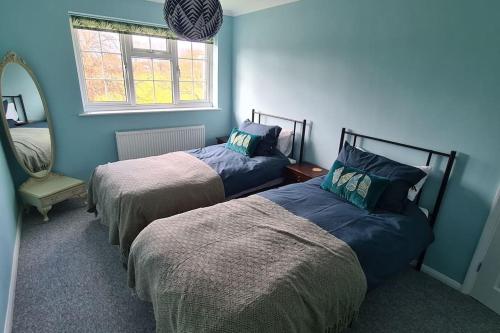two beds in a room with blue walls and a mirror at Haven Cottage - adjacent to beach and promenade in Walmer