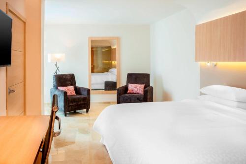 バランキージャにあるフォー ポイント バイ シェラトン バランキージャのベッド1台と椅子2脚が備わるホテルルームです。