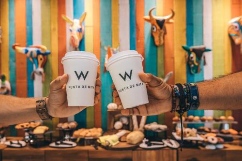 two people holding coffee cups in their hands at W Punta de Mita in Punta Mita