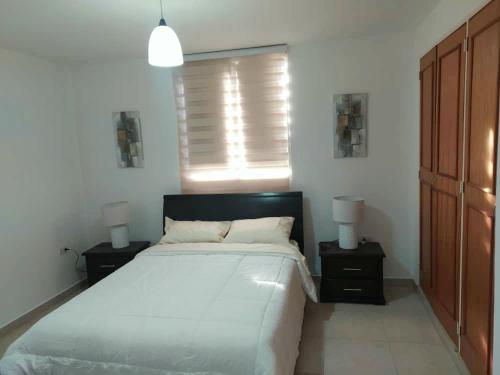Confortable apartamento en Marina del Rey Lecheria في El Morro de Barcelona: غرفة نوم بسرير كبير وموقف ليلتين