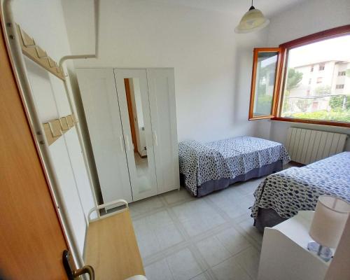 una piccola camera con due letti e una finestra di Appartamento Castiglioncello 600 mt dal mare a Castiglioncello