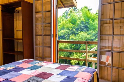a bedroom with a bed and a large window at Pousada Trem das Cores in Gonçalves