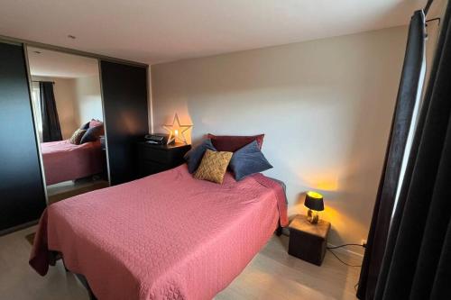 1 dormitorio con 1 cama con colcha rosa en Nyoppusset 2 roms leilighet til leie på Rykkinn, en Bærums Verk