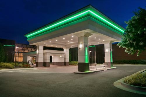 Holiday Inn Washington-Dulles International Airport, an IHG Hotel في ستيرلينغ: مبنى كبير عليه اضاءة خضراء بالليل