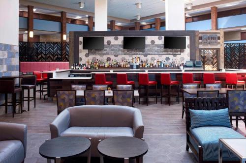 um restaurante com um bar com mesas e cadeiras em Four Points by Sheraton Detroit Novi em Novi