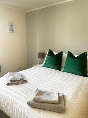 a bed with green pillows and towels on it at Waverley Court in Fort William