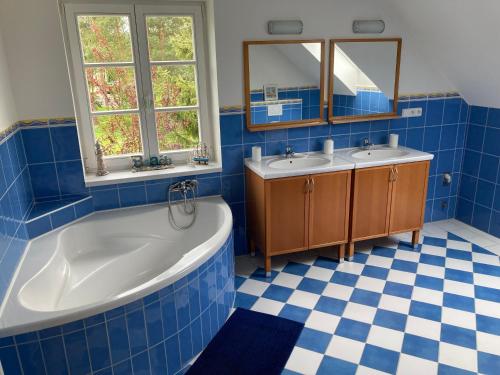 a blue tiled bathroom with two sinks and a tub at Chalupa u Pavelků 