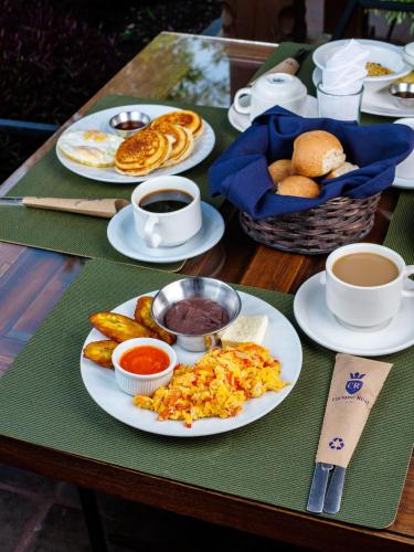 a table with plates of food and cups of coffee at Hotel Cacique Real in Antigua Guatemala