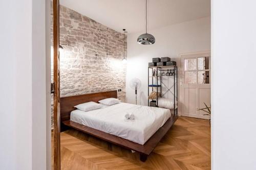 1 dormitorio con cama y pared de ladrillo en Harmonie, en Nimes