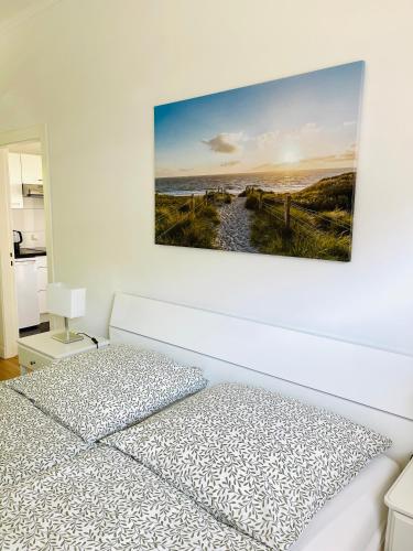 a white bedroom with a bed and a painting on the wall at Bungalow-Wohnung nahe Flughafen Hamburg in Norderstedt