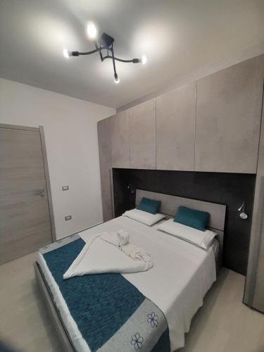 um quarto com uma grande cama branca com almofadas azuis em SOLE E MARE VILLASIMIUS Codice IUN R1681 em Villasimius