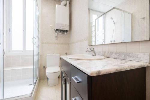 uma casa de banho com um lavatório, um WC e um espelho. em Ramblas Waterfront Stay em Barcelona