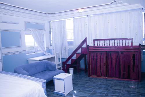 a bedroom with a bed and a blue chair at Hôtel Amazone in Cotonou