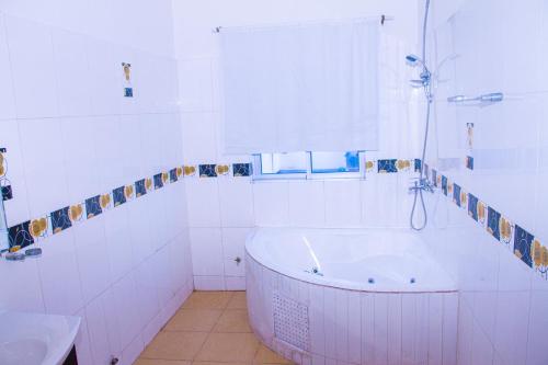 La salle de bains blanche est pourvue d'une baignoire et d'un lavabo. dans l'établissement Hôtel Amazone, à Cotonou