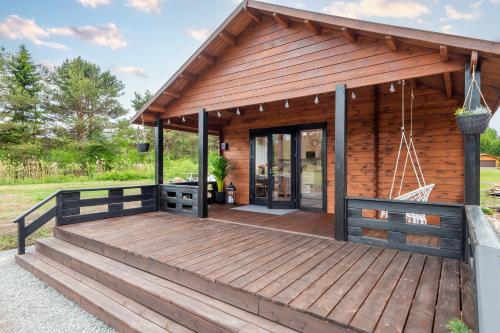 a log cabin with a wooden deck at Forrest Guest House in Ķesterciems