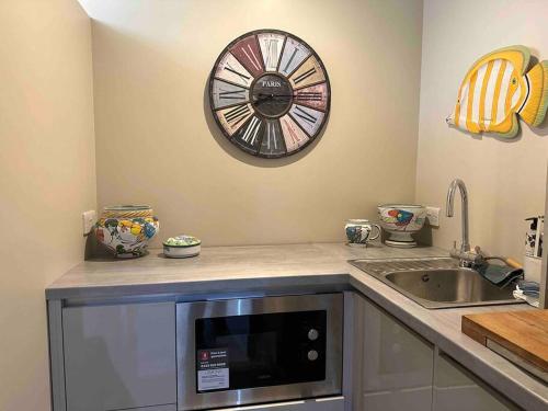 una cocina con fregadero y un reloj en la pared en New luxury self-contained studio en South Cadbury