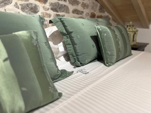a bed with four green pillows on it at PortaDelMare deluxe suites in Hydra