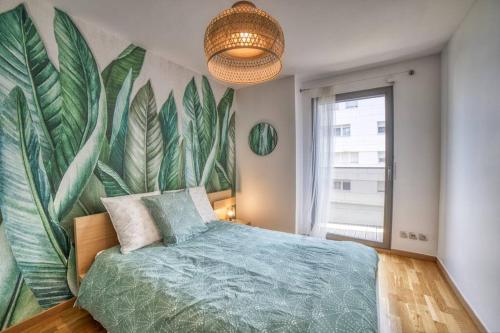 1 dormitorio con un gran mural de hojas en la pared en COSY FLAT direct access Genève-Airport-Palexpo, en Annemasse