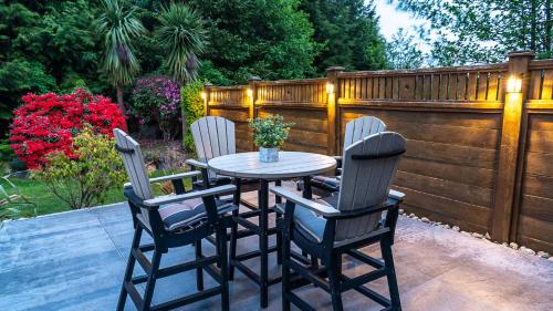 une table et quatre chaises sur la terrasse dans l'établissement Wild Pacific Guest Suites, à Ucluelet