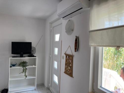 Habitación blanca con TV y ventana en Apartmani Fijan en Pag