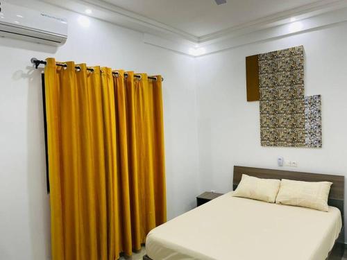 1 dormitorio con cama y cortina amarilla en Appartement meublé T3 N 5 Résidence LES 11 PLURIELLES, 
