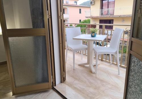 een glazen schuifdeur naar een balkon met een tafel en stoelen bij Vintage Home in La Caletta