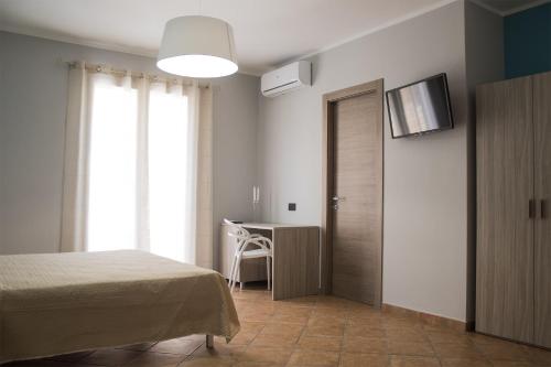 a bedroom with a bed and a desk and a television at Incanto Luxury Rooms in Lampedusa