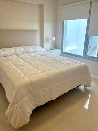 a large bed in a bedroom with a large window at Departamento premium para 3 personas in Puerto Madryn