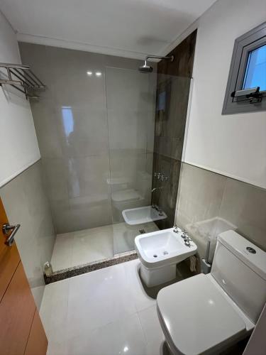 a white bathroom with a toilet and a sink at Departamento premium para 3 personas in Puerto Madryn