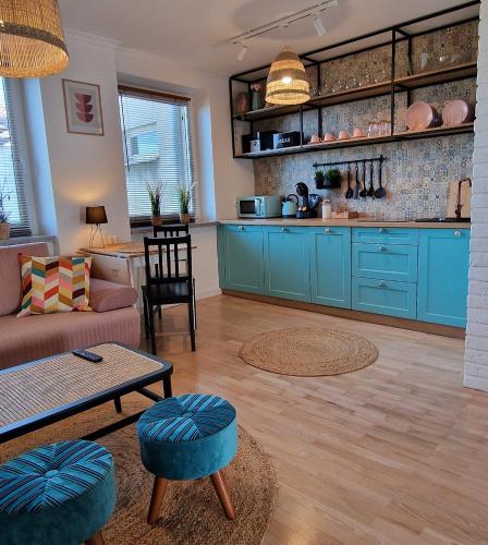 a living room with blue cabinets and a kitchen at Apartament Boho in Biłgoraj