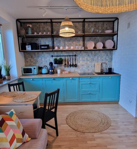 una cocina con armarios azules y una mesa con sillas en Apartament Boho, en Biłgoraj