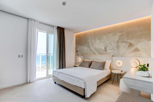 a bedroom with a bed and a large window at Hotel Mirafiori in Lido di Jesolo