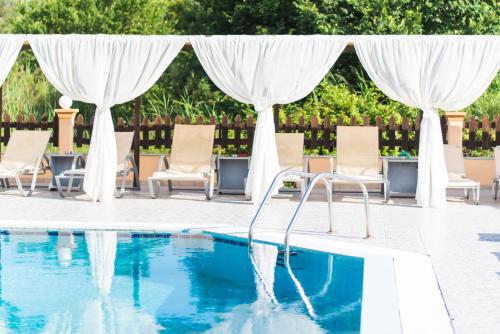 a swimming pool with chairs and a canopy and a swimming pool at Sandy Beach Complex - Annexe Building in Kavos