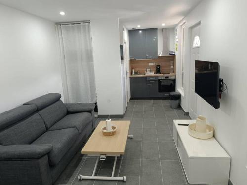 a living room with a couch and a table at Petite maison avec jardin in Montluçon