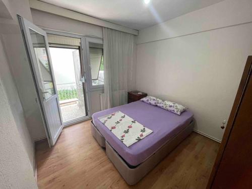 a small bedroom with a purple bed and a window at Dikili Sahilde Denize Sıfır Daire in Dikili