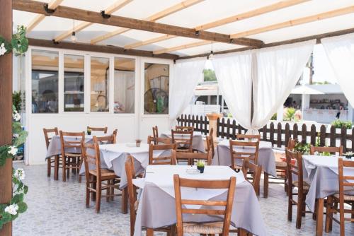 a restaurant with white tables and wooden chairs at Sandy Beach Annexe in Kavos